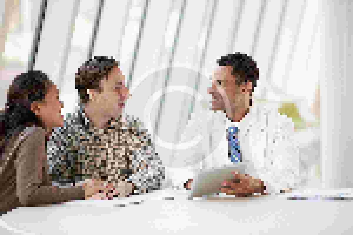 Doctor Using Tablet Computer Discussing Treatment With Patients